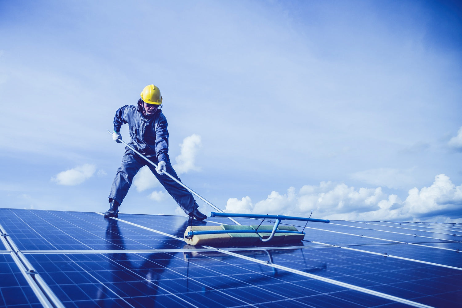 Mann reinigt eine Aufdach-PV-Anlage.