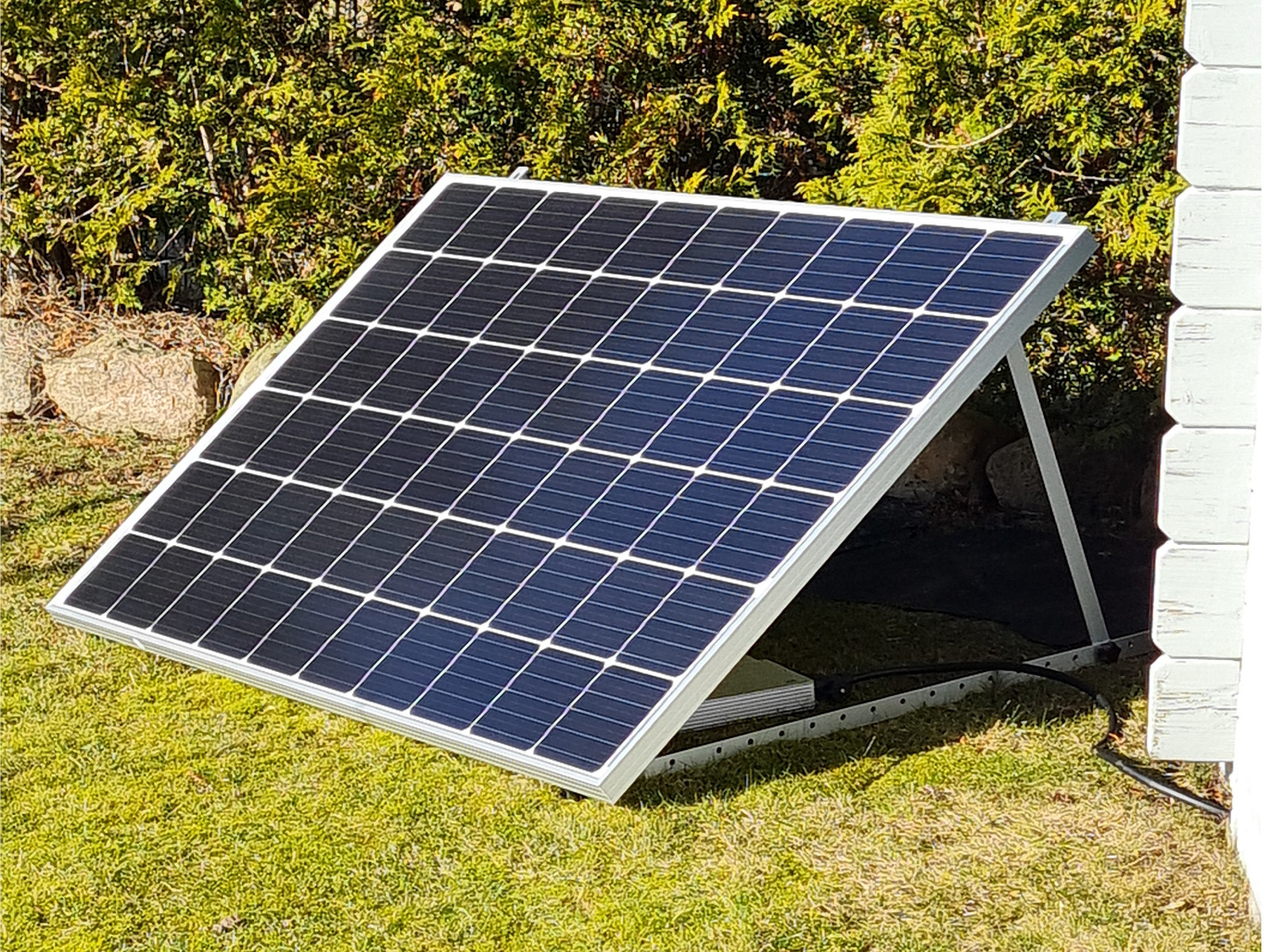 Polykristallines Solarmodul mit Silbernen Triangel-Aufständerungs-System im Garten.